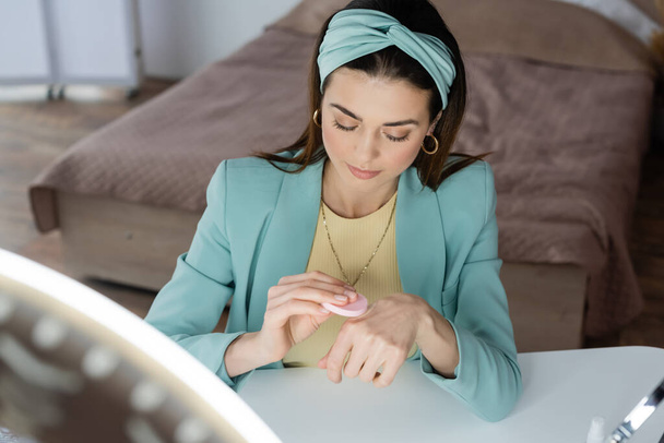 blogueiro de beleza elegante usando esponja cosmética na mão perto da luz do anel - Foto, Imagem