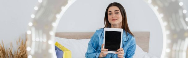 fröhliche Mode-Bloggerin im stylischen Pyjama zeigt digitales Tablet in der Nähe von verschwommenem Kreislicht, Banner - Foto, Bild
