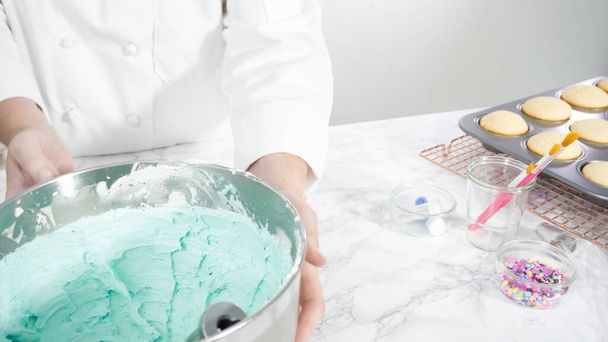 Adım adım. Denizkızı temalı vanilyalı kekler için tereyağlı krema yapmak için mutfak mikserinde malzemeler karıştırılıyor.. - Fotoğraf, Görsel