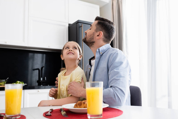 happy father and daughter looking at each other near breakfast in kitchen - Foto, Bild