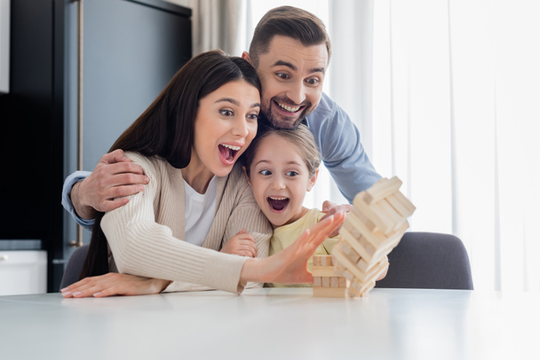 verbaasd familie breken houten toren tijdens het spelen samen  - Foto, afbeelding