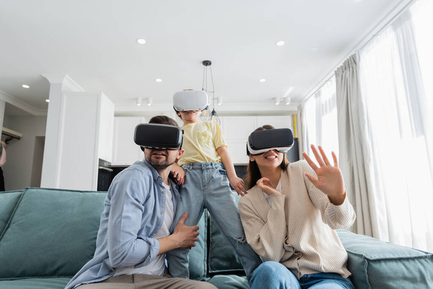 scared family gaming in vr headsets on sofa in living room - Foto, Bild