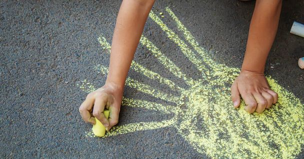 child draws with chalk on the pavement. Selective focus. - Photo, Image