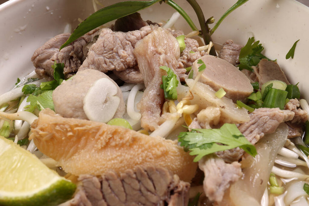 Vietnamská poh hovězí nudle polévka vývar s hovězím kuličkovým hovězím masem hovězí maso výhonky thajská bazalka vápno v misce na dřevěném stole - Fotografie, Obrázek