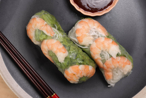 Βιετναμέζικες γαρίδες δείτε μέσα από ριζόχαρτο άνοιξη ρολό πράσινη σάλτσα λαχανικών σε σκούρο πιάτο chopsticks ξύλινο τραπέζι - Φωτογραφία, εικόνα