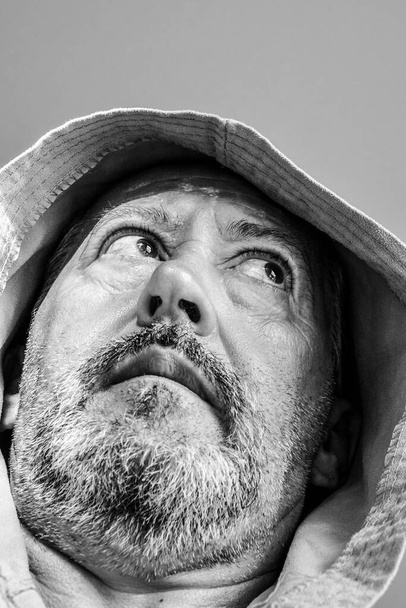 Smutný muž středního věku s šedým vousem a kapucí na hlavě                              - Fotografie, Obrázek