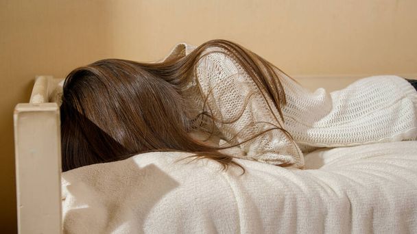 10代の少女がベッドの上で枕に倒れて泣いて動揺した。十代のうつ病や社会問題 - 写真・画像