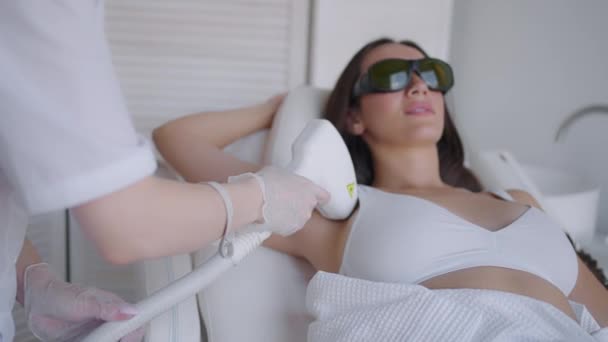 A female cosmetologist does laser hair removal of the armpits in a beauty salon. Removal of hair from the armpits. Beauty and clean skin - Footage, Video