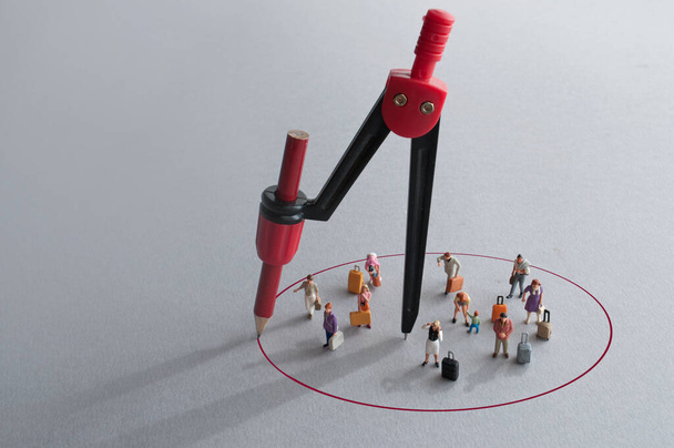 Compass with red pencil circle around miniature travellers - Φωτογραφία, εικόνα