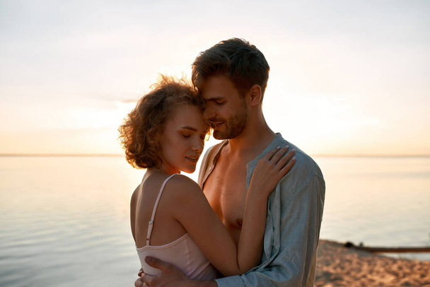 Beautiful young caucasian lovers hugging at sunset - Fotografie, Obrázek