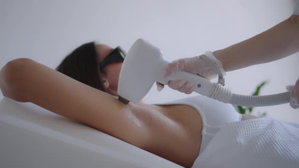 Kobieta kosmetolog robi laserowe usuwanie włosów pod pachami w salonie piękności. Usunięcie włosów z pach pachy. Piękno i czysta skóra - Materiał filmowy, wideo