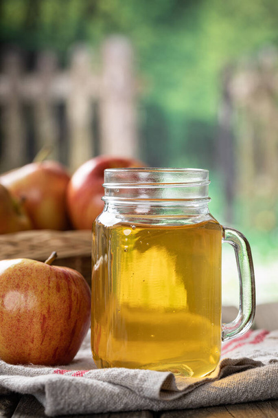 Closeup of a glass of apple juice and fresh apples with rural background - Foto, Imagem