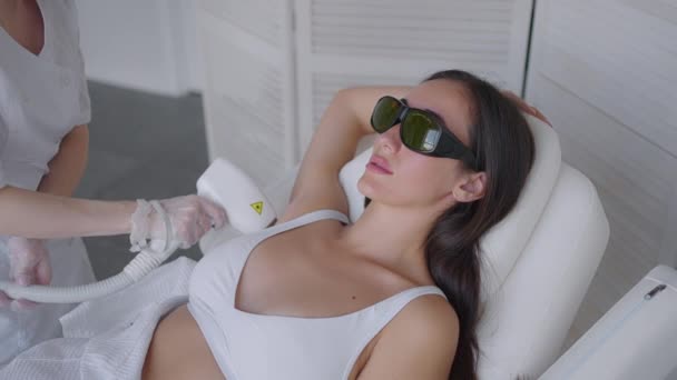 A female cosmetologist does laser hair removal of the armpits in a beauty salon. Removal of hair from the armpits. Beauty and clean skin - Séquence, vidéo