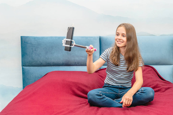 Beautiful little blogger girl recording a video blog at home with a selfie stick - Zdjęcie, obraz