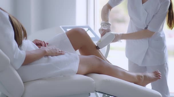 Depilacja laserowa. Kobieta poddawana laserowej depilacji na nogach. Beauty laser leczenie salon kosmetyka kosmetologia profesjonalny zawód pielęgnacja ciała koncepcja - Materiał filmowy, wideo