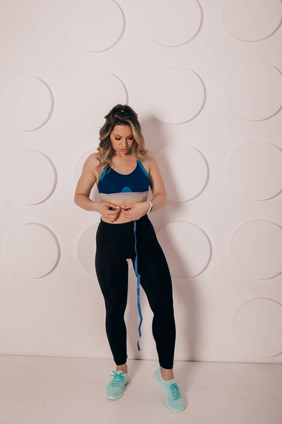 Woman measuring her waist with centimeter tape at home. Fast weight loss concept. - Photo, Image