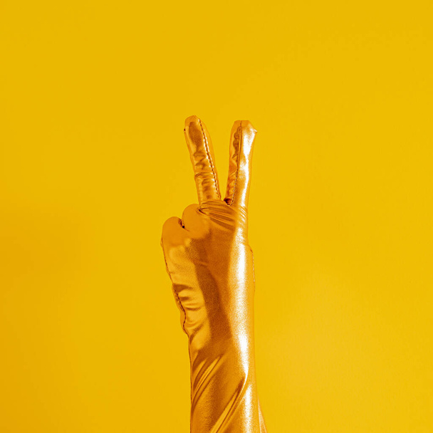 mano con guante dorado y número dos sobre fondo amarillo soleado de verano. arte abstracto de verano moderno - Foto, Imagen