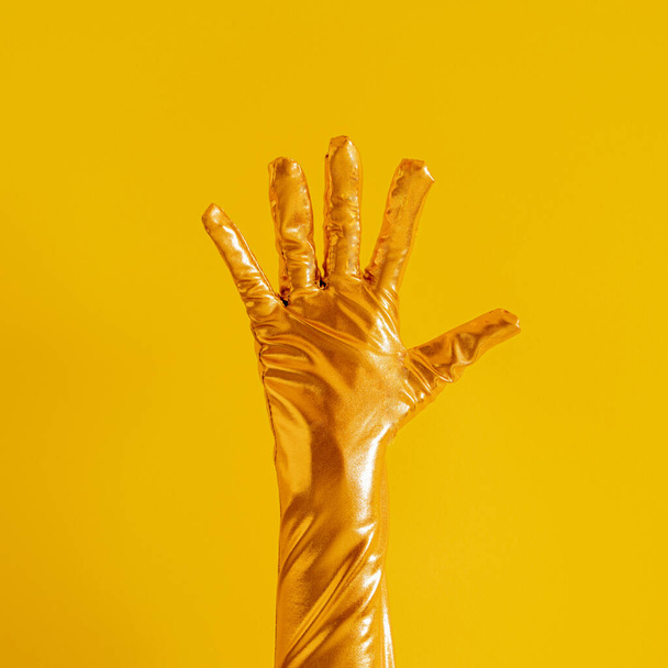 ręka ze złotą rękawicą i numer pięć na żółtym słonecznym tle lata. nowoczesna letnia abstrakcyjna sztuka - Zdjęcie, obraz