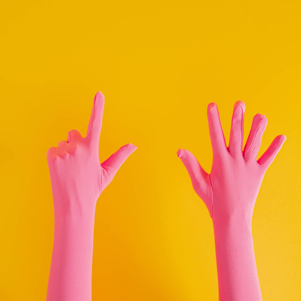 ピンクの手袋と黄色の晴れた夏の背景に7番目の手。現代の夏抽象美術 - 写真・画像