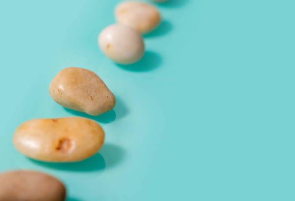 5 small brown stones, similar to pebbles, lie diagonally on a turquoise background. - Foto, afbeelding