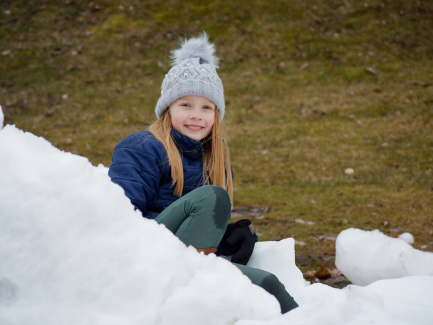 Winterspaß. Fröhliches Kind mit Hut spielt Schneebälle - Foto, Bild