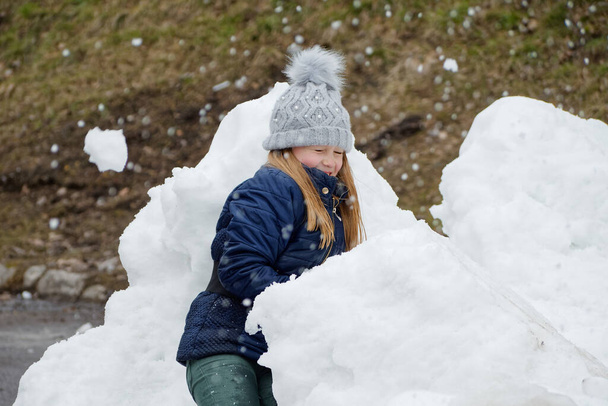 зимнее веселье. весёлый ребёнок в шляпе играет в снежки 2020 - Фото, изображение