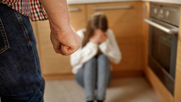 Őrült férfi veri és három fiatal nőt sír a padlón. A családon belüli erőszak, a szülői bántalmazás és a családi agresszió fogalma. - Fotó, kép