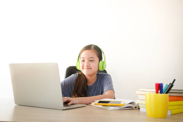 Asiatische Schulmädchen lernen online von zu Hause aus durch Videoanrufe. Verwendung eines Laptops zur Kommunikation mit Lehrern. Konzept der Online-Bildung. Soziale Distanzierung zur Verringerung der Ausbreitung des Coronavirus. - Foto, Bild