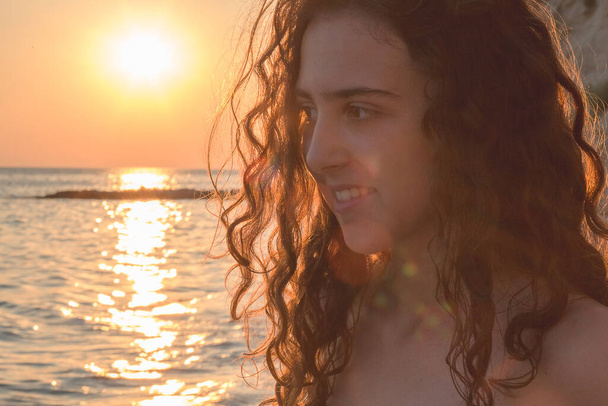Beautiful, young teen girl with curly hair posing by the sea - Fotó, kép