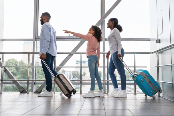 Μαύρη οικογένεια που ταξιδεύουν μαζί, περιμένοντας την άφιξη του αεροσκάφους - Φωτογραφία, εικόνα
