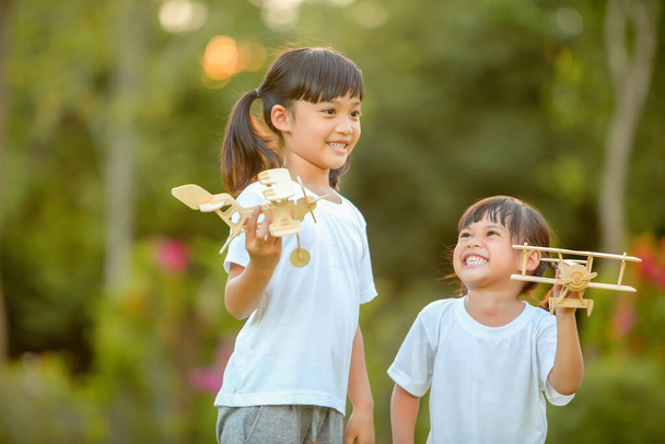 公園で自然をテーマにしたおもちゃの飛行機を遊んでいる可愛い女の子アジア2人。無限の想像力を飛んでの小さな夢.これは、開発を増加させ、学習スキルを向上させます. - 写真・画像