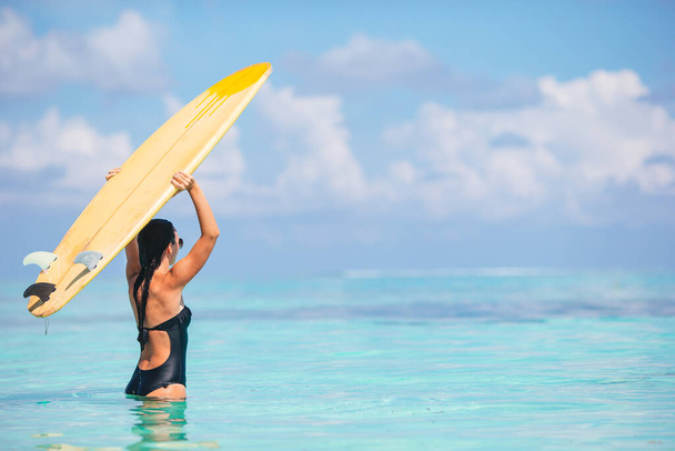 Beautiful surfer woman ready to surfing in turquoise sea, on stand up paddle board at exotic vacation - Foto, immagini