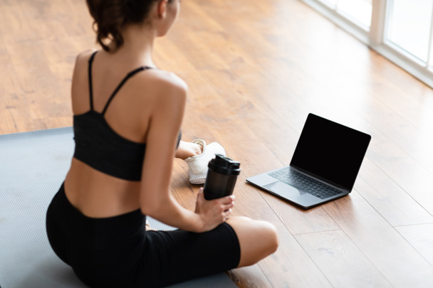 Young woman sitting on mat with pc - Photo, Image