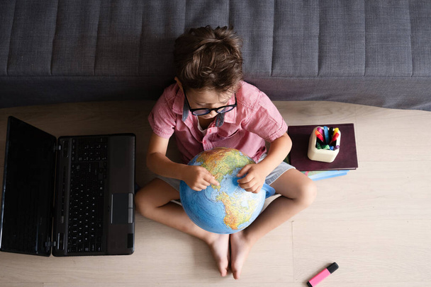 Aranyos kaukázusi fiú használ laptop néz a világ tanul otthon - Fotó, kép