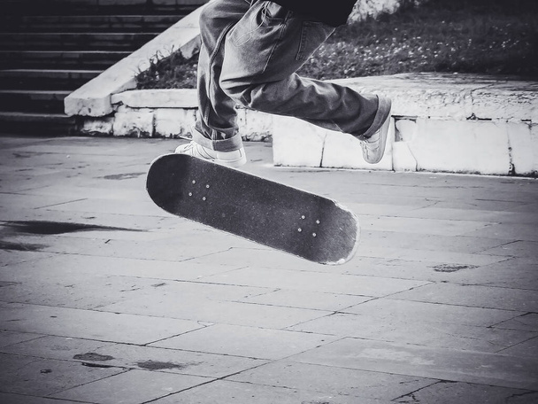 Der Typ macht einen Flip-Jump auf einem Skateboard auf der Straße. Skateboard-Trick. Schwarz-Weiß-Foto - Foto, Bild