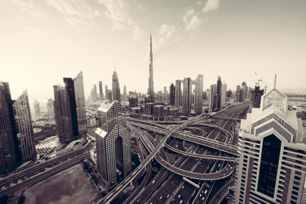 Luftaufnahme der Skyline von Dubai Downtown, Autobahnen oder Straßen in den Vereinigten Arabischen Emiraten oder den VAE. Finanzviertel und Geschäftsviertel in einer intelligenten urbanen Stadt. Wolkenkratzer und Hochhäuser bei Sonnenuntergang. - Foto, Bild