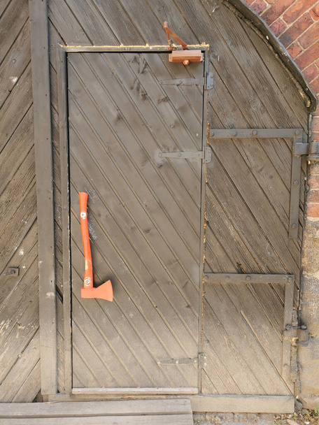Brązowe drewniane drzwi z rączką w kształcie czerwonej siekiery w kawiarni znajdującej się w kamiennej ścianie Zamku Vyborg w mieście Vyborg - Zdjęcie, obraz