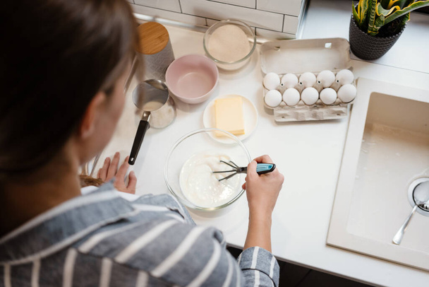 Καυκάσια μελαχρινή γυναίκα κάνει ζύμη τηγανίτα στο σπίτι κουζίνα - Φωτογραφία, εικόνα