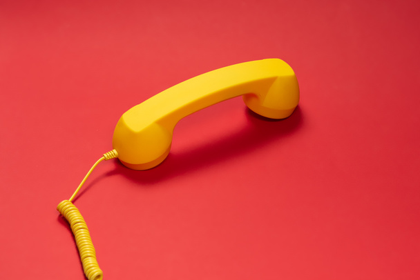 Yellow handset on red background. Copy space.  - Foto, Imagen