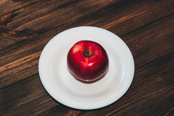 Μήλο σε ένα άδειο λευκό πιάτο. Διατροφή και ακατέργαστα τρόφιμα έννοια. - Φωτογραφία, εικόνα