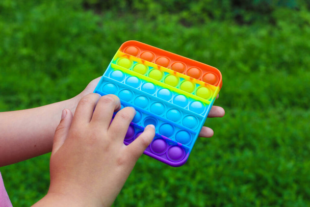 子供の手は正方形の多色の泡おもちゃのストレス感覚ポップそれを再生されます. - 写真・画像