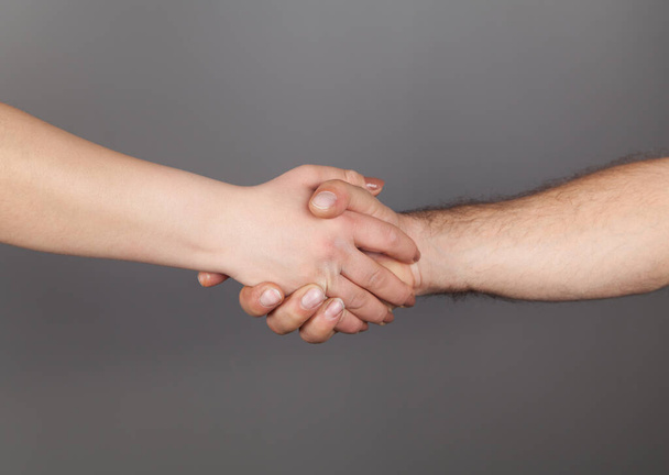 Ruce muže a ženy drží pohromadě, šedé pozadí. - Fotografie, Obrázek