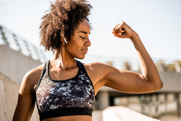 Afro athlete woman flexing and showing muscles. - 写真・画像