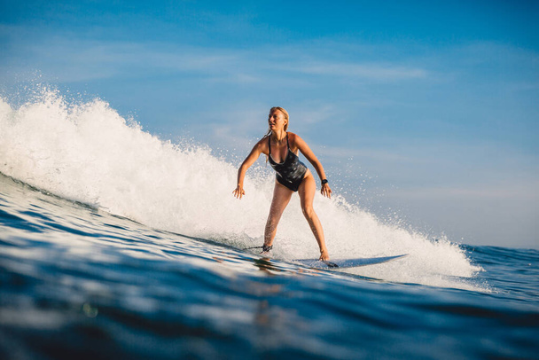 Surfer meisje rijdt op golf op surfplank. Sportieve vrouw in zee tijdens het surfen. - Foto, afbeelding