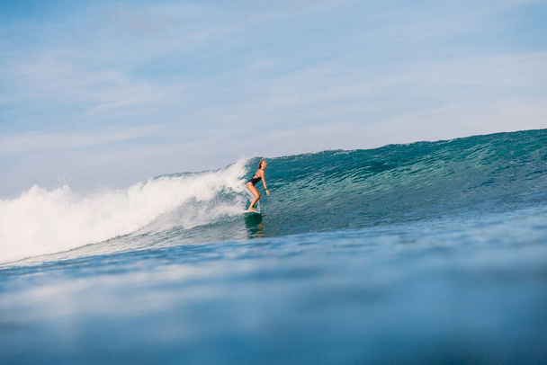 Surfermädchen am Surfbrett auf blauer Welle. Sportliche Frau beim Surfen im Meer. - Foto, Bild