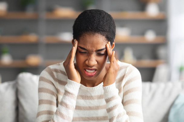 Joven mujer afroamericana que sufre de dolor de cabeza o migraña en casa - Foto, Imagen