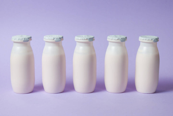 プロバイオティクスとプレバイオティクスを含むボトル乳製品は、薄紫の背景に飲みます. - 写真・画像