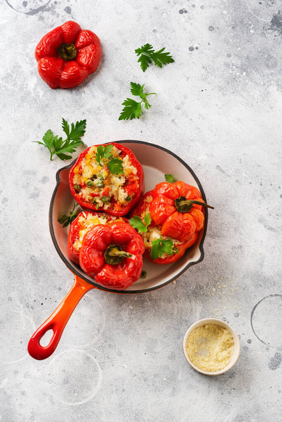 Red bell peppers stuffed with rice and vegetables on cast iron pan on gray concret background - Foto, Imagem