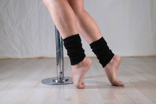 Details der Füße einer Pole-Tänzerin in einer Tanzstunde. Sie wärmt sich auf, bevor sie auf die Stange steigt. Konzept Tanz, Sport. - Foto, Bild