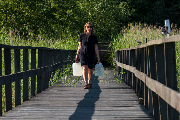 Ekero, Suède Une femme porte des cruches d'eau potable sur un quai. - Photo, image